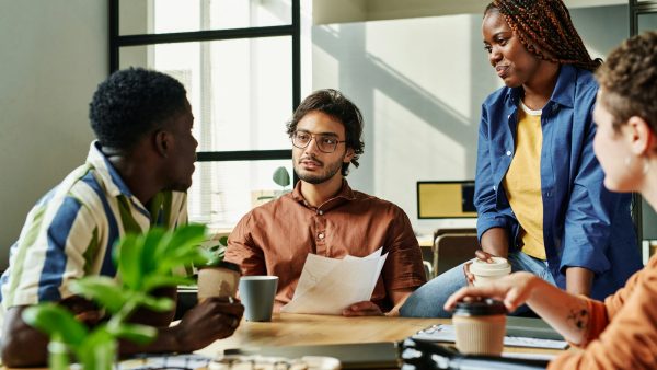 Young confident manager with papers talking to colleague